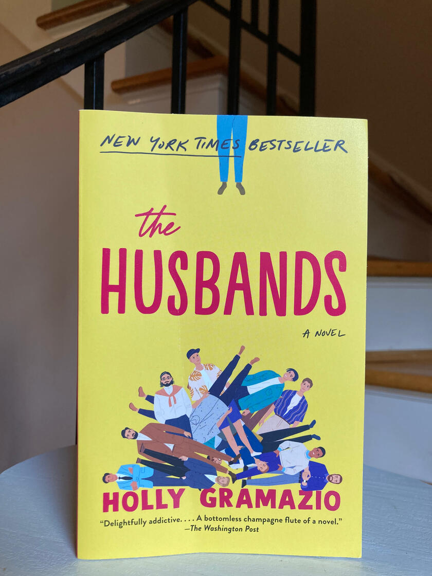 “The Husbands” by Holly Gramazio “The Husbands” by Holly Gramazio Book in front of a staircase.