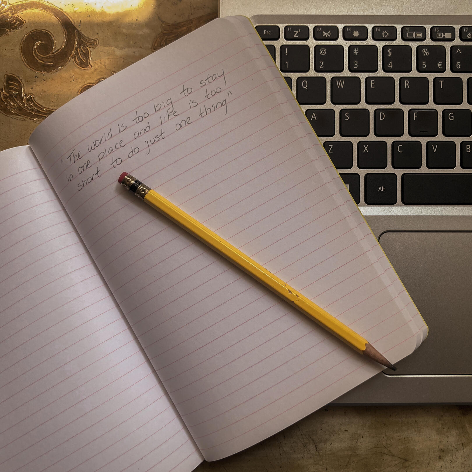 Notebook laying on a laptop, with a handwritten quote.