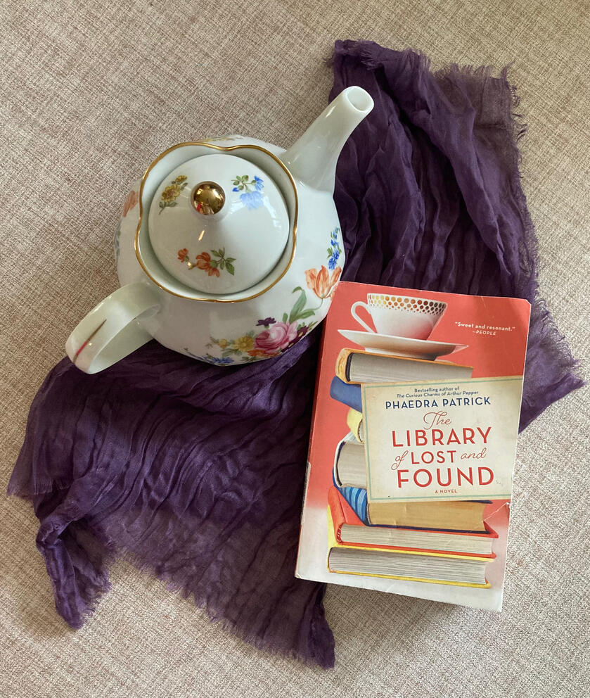 Teapot on a tablecloth, next to a book titled "The Library of Lost and Found"